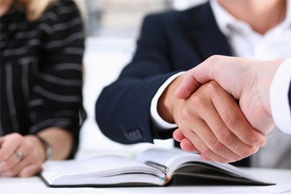 Men shaking hands with woman in the background